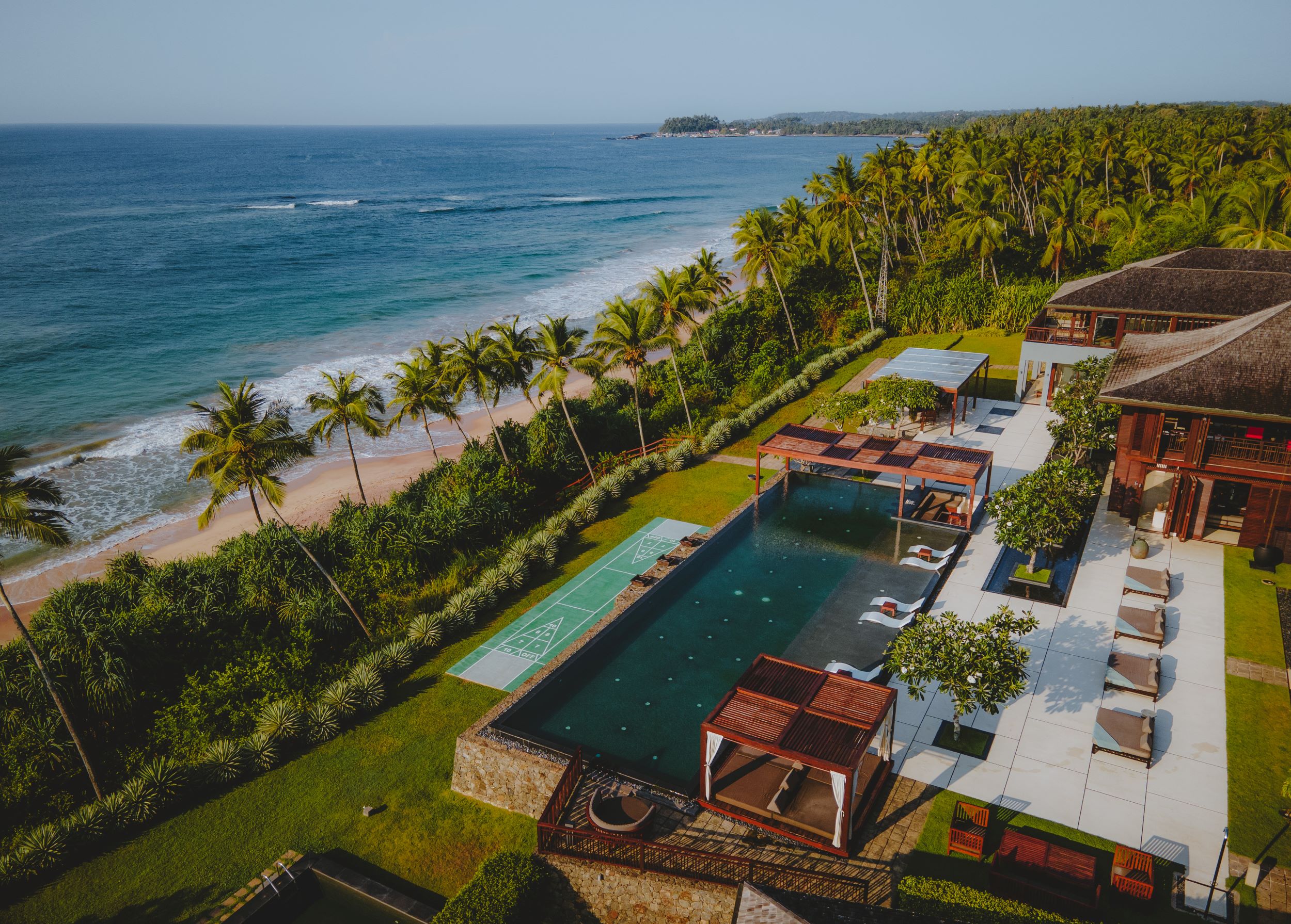 Aerial drone view of luxurious Caribbean villa overlooking turquoise ocean at sunset, perfect for tokenized fractional real estate ownership investing starting at $100